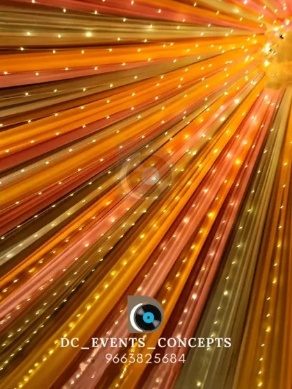 A look up at a colorful ceiling decoration made of draped fabric and embedded fairy lights. This design adds vibrancy and warmth to the entire venue.