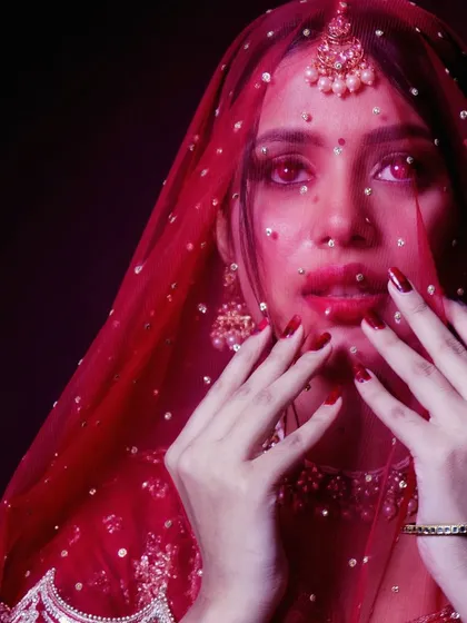 An artistic close up shot of the bride through her sequined red veil. This creates a dreamy, slightly mysterious effect, focusing on her eyes and red lipstick.