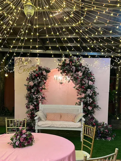 A romantic 'Better Together' setup perfect for an anniversary or engagement party. The fairy light canopy, pink floral arch, and elegant white bench create a perfect photo opportunity.