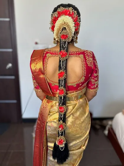 An elaborate floral hair braid is a hallmark of South Indian bridal beauty. This hairstyle for Prerana features a stunning arrangement of red and white flowers, creating a dramatic and unforgettable look from the back.
