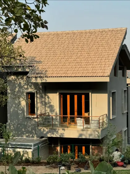 The exterior of the 6AM House under construction. The design uses a simple pitched roof and a combination of concrete and wood, creating a modern yet grounded architectural form.