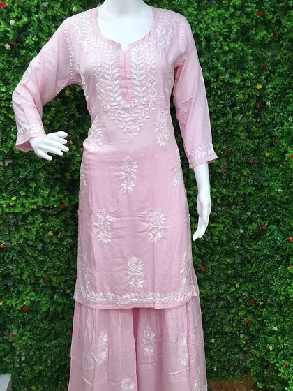 A soft pink Lucknowi Chikankari kurti paired with a matching sharara. The delicate white embroidery gives it a very feminine and graceful look, perfect for daytime events.