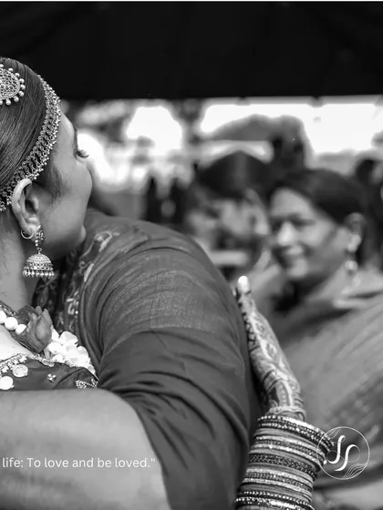 A touching black and white photo of the bride sharing a hug with a family member.