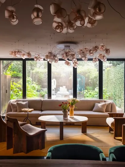 Another angle of the living room, showing how the Bocci 100 series interacts with natural light from the large windows, its glass forms catching and refracting the daylight.
