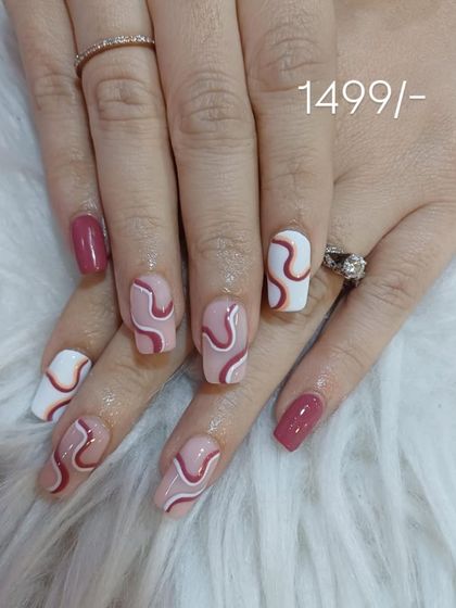 This design plays with shades of pink and white, featuring abstract wavy lines on a nude base. The combination of solid mauve and patterned nails creates a cohesive, stylish look.