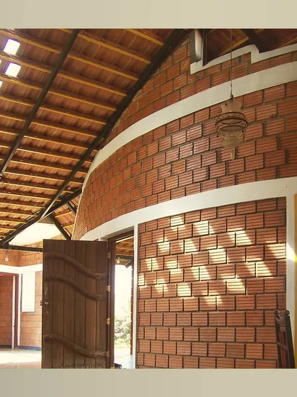 The interior of the farmhouse, with a curved wall made of hollow clay blocks and a high, sloping roof that allows for ample light and air.