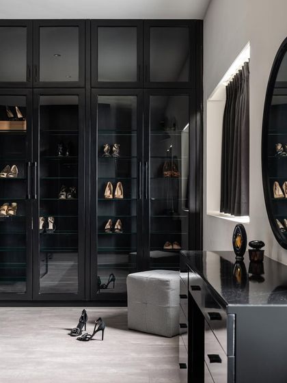 A dedicated shoe closet within the walk-in, featuring glass doors and angled shelves to beautifully display the collection. The space is both highly functional and incredibly chic.