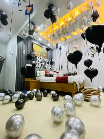 A modern and chic birthday room setup using a black and silver color scheme. This design includes helium balloons with long ribbons holding personal photos, adding a unique and sentimental touch to the celebration.