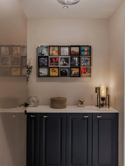 Elevate your entrance with a statement piece. This indigo blue foyer unit features elegantly routed shutters, a crisp white European membrane top, and sleek black knobs, all crowned by a captivating grid of wall art.