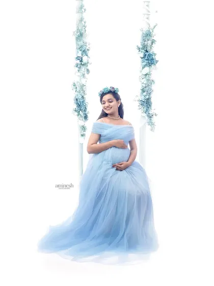 A slightly different angle of the floral swing setup, capturing a joyful and serene smile. These high-key shots are perfect for creating a light and airy feel for your pregnancy photos.