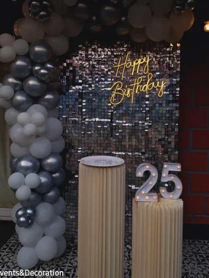 The silver and white balloon arch beautifully frames the shimmer wall for this 25th birthday celebration.