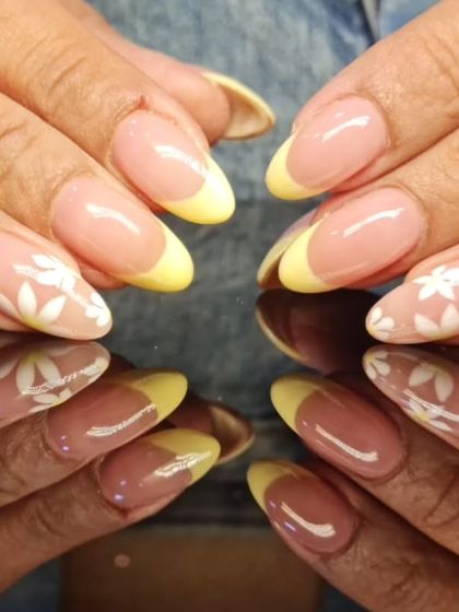 A playful twist on the French manicure, with cheerful yellow tips and delicate white floral art on accent nails.