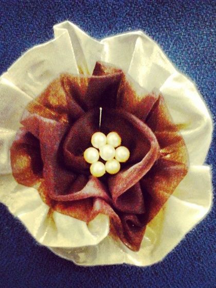 A handmade fabric flower created in my studio. These custom embellishments, often finished with a pearl center, are used to add a unique, three-dimensional touch to gowns and accessories.