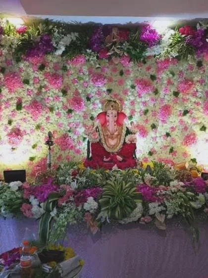 A full floral wall of pink and white flowers serves as a stunning backdrop for this Ganpati setup. The wide arrangement provides a grand and immersive floral experience for your home celebration.