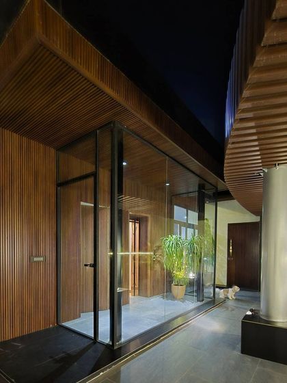 A glass-enclosed terrace space with elegant wood-paneled walls and ceiling. This design creates a seamless transition between the interior and exterior, offering a comfortable place to enjoy the view with a pet dog resting nearby.