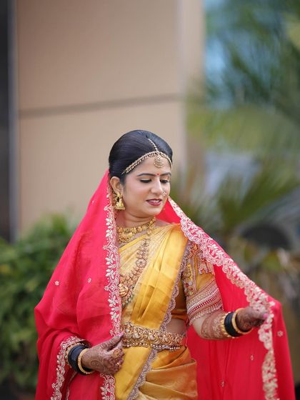 Bride Rashmi looks divine in a traditional yellow Kanchipuram saree with a red veil. This is a classic Muhurtham style, and her makeup is kept warm and golden to match the richness of her attire.