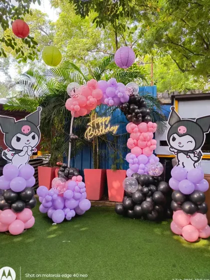 A full view of the outdoor Kuromi-themed party. The setup includes a balloon arch, character pillars, and hanging paper lanterns that add to the festive atmosphere.