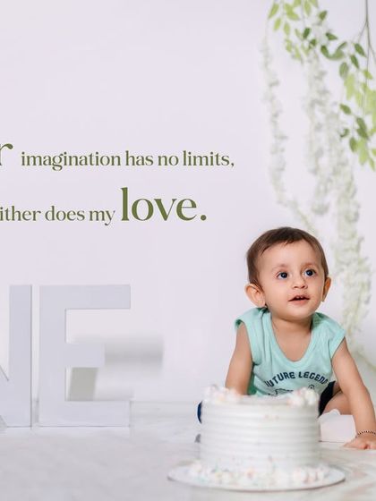 A quiet moment during a first birthday cake smash session. This minimalist studio setup with soft green accents puts all the focus on the little one's curious expression.
