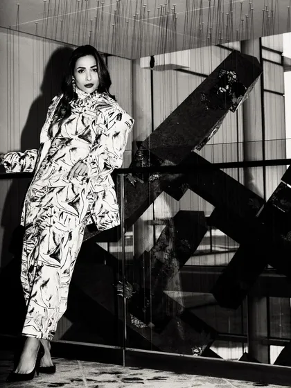 A full-length black and white shot of Malaika Arora. The geometric background and strong shadows create a high-fashion, graphic feel.