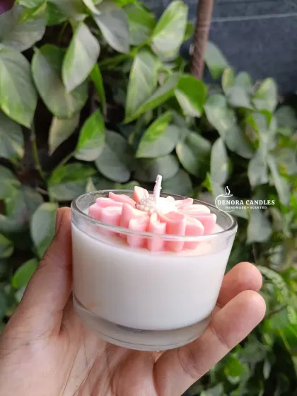 A small, pink flower jar candle held in hand.