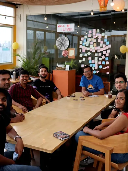 A full table of friends enjoying a game night. The 'Wall of Love' behind them is filled with notes and memories from our wonderful community.