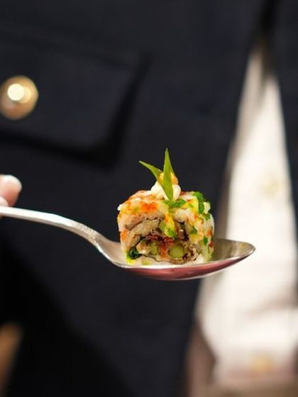 A single, perfectly crafted canapé served on a spoon. This one-bite wonder is an example of our focus on elegant, refined presentation for luxury brand events.