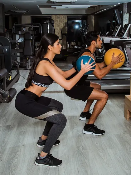 A high-quality shot of a partner squat with medicine balls, emphasizing our focus on form and community.