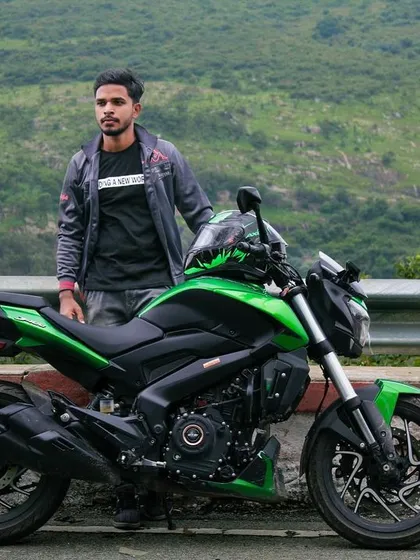 A full shot of a rider and his stock green Dominar 400, showcasing the bike's design against a natural setting.