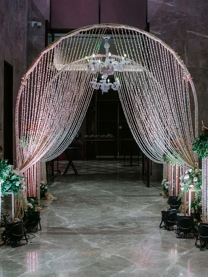 We design grand entrances that leave a lasting impression. This stunning archway, created with thousands of shimmering crystal beads and a classic chandelier, offers a truly luxurious welcome.