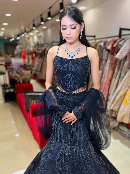 A detailed shot of the bodice and sleeves of the navy blue lehenga. The delicate straps and tassel details on the blouse add a touch of modern flair.