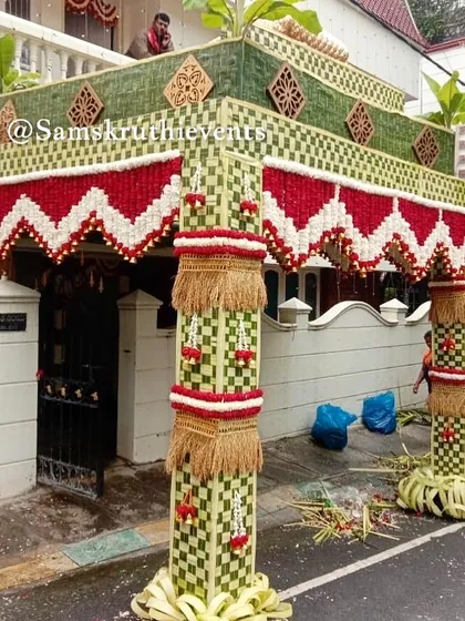 A grand 'Chappara' being set up in front of a home. This design features intricate weaving patterns with red and white flowers, creating a majestic and traditional welcome for guests.