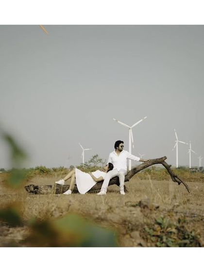 A beautifully composed pre-wedding photo, using a fallen tree as a natural prop in a vast, open landscape.