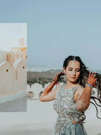 A beautiful portrait of the bride, her hair blowing in the wind, with the Udaipur cityscape in the background.