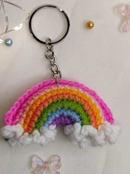 A vibrant rainbow keychain with fluffy white clouds, because who doesn't love carrying a rainbow around?