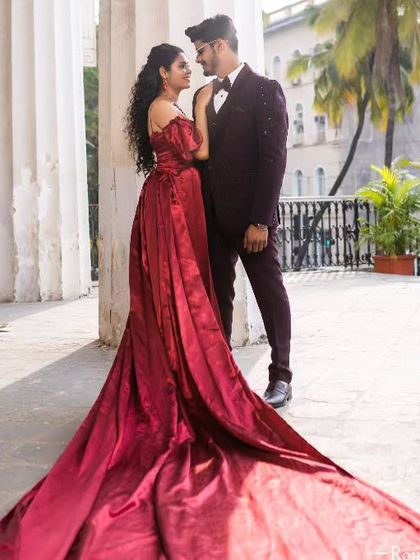 A closer look at the rich texture and flow of the maroon taffeta gown. The off-the-shoulder neckline and long trail create a look that is both classic and romantic.
