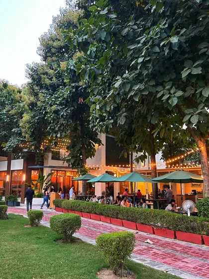 A wide view of the cafe and its beautiful surroundings, including the brick path and lush lawns.