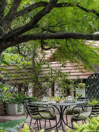 The gardens offer many quiet nooks for conversation, with wrought-iron and stone furniture placed thoughtfully under the shade of old trees.
