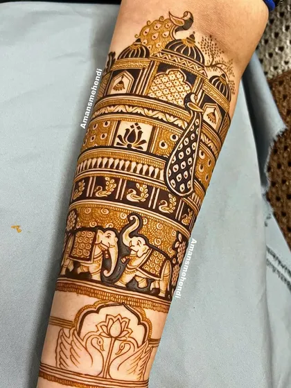 A detailed view of a bridal arm design. This section features bands of patterns including swans, a lotus, elephants, and a majestic peacock in front of a palace.