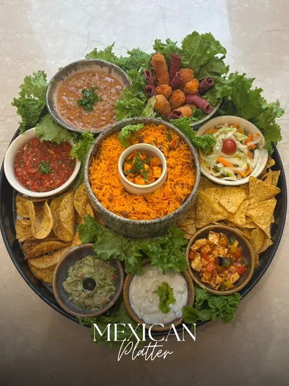 Our Mexican Platter is a fiesta of flavors. It features spicy rice, nachos with salsa and guacamole, bean dip, and other zesty bites, all arranged on a bed of fresh lettuce for a vibrant presentation.