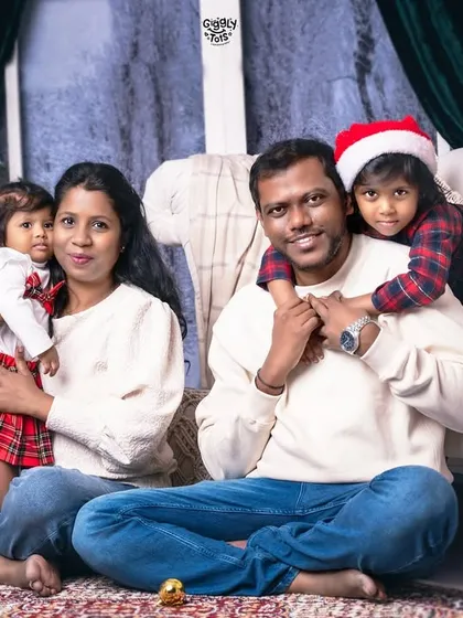 A happy family of four, dressed in cozy sweaters, enjoying their Christmas photoshoot together.