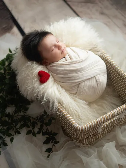 A tiny felt heart adds a touch of love to this simple and sweet newborn setup. The baby is wrapped snugly in a neutral swaddle, resting in a soft, cozy basket.