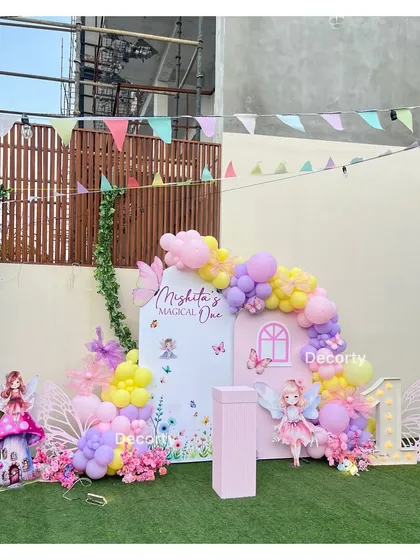 A wider view of the outdoor fairy party setup, showing the full backdrop against a green lawn.