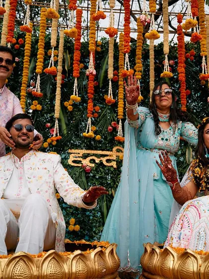 A candid moment of joy during the Haldi ceremony. The backdrop of hanging marigold flowers adds to the traditional and festive feel of the celebration.