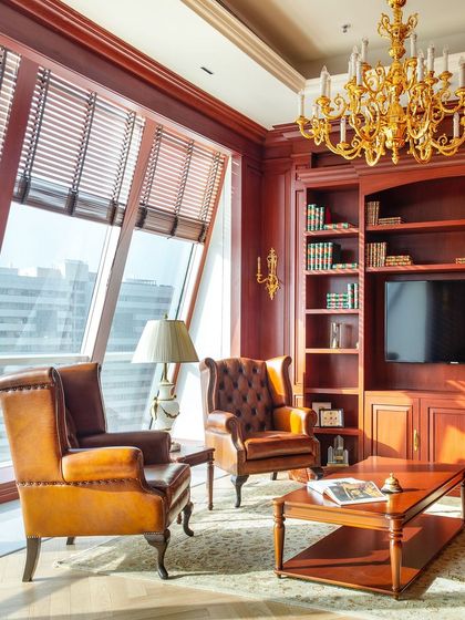 A seating area within the Paras Buildtech director's office offers a comfortable space for meetings. The classic leather wingback chairs and large windows with city views create a space that is both functional and elegant.