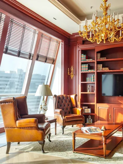 A seating area within the Paras Buildtech director's office offers a comfortable space for meetings. The classic leather wingback chairs and large windows with city views create a space that is both functional and elegant.