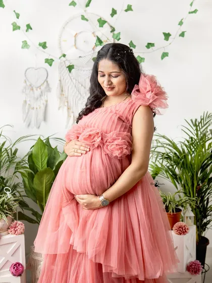 A solo portrait is all about celebrating the mother to be. Here, she radiates peace and happiness in one of our elegant, tiered maternity gowns, set against a fresh, botanical backdrop in our studio.