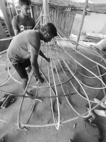 An artisan carefully works on the intricate cane structure of the Biergarten light. This collaborative process, combining our design with their traditional techniques, is central to how we bring soul into our projects.