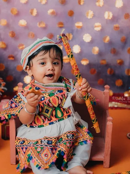 A joyful expression from our little Garba dancer. The colorful setup with traditional umbrellas creates a festive atmosphere.