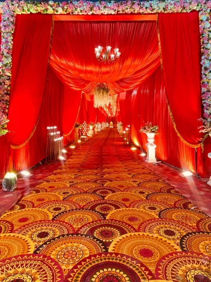 A classic red carpet entrance with heavy red draping and floral borders, creating a timeless and regal welcome for guests.