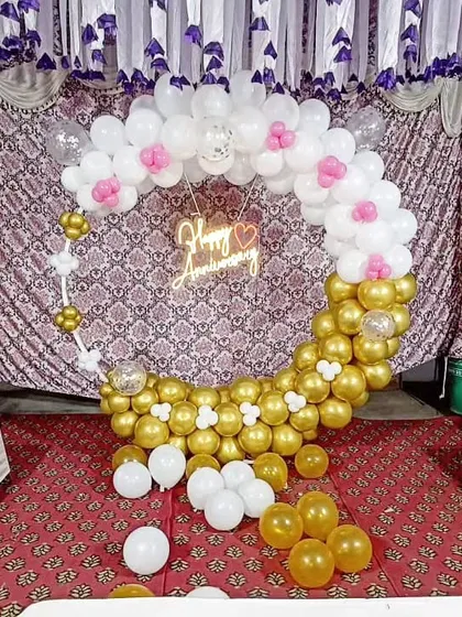 The gold and white anniversary balloon arch, accented with small pink and white balloon flowers for a touch of sweetness.